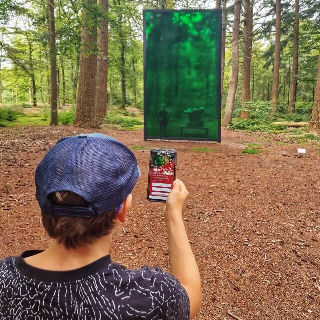 Kröller-Müller Museum en Nationaal Park de Hoge Veluwe met kinderen. Heel leuk voor wat oudere kinderen en tieners: Kröller-Müller Museum heeft een eigen geocaching route. Echt wat voor onze jongen, die is gek op digitaal speuren. Je kiest een route langs 5 of 11 kunstwerken, wij gingen voor de lange route. Al speurend loop je dus dwars door de beeldentuin. Bij ieder kunstwerk dat je vindt, moet je een vraag beantwoorden en krijg je meer informatie als je op de i klikt. Zoals hier bij het kunstwerk Green Room van Marien Schouten. Uiteindelijk ga je op zoek naar een kunstschat en krijg je een kleine beloning in de museumwinkel.