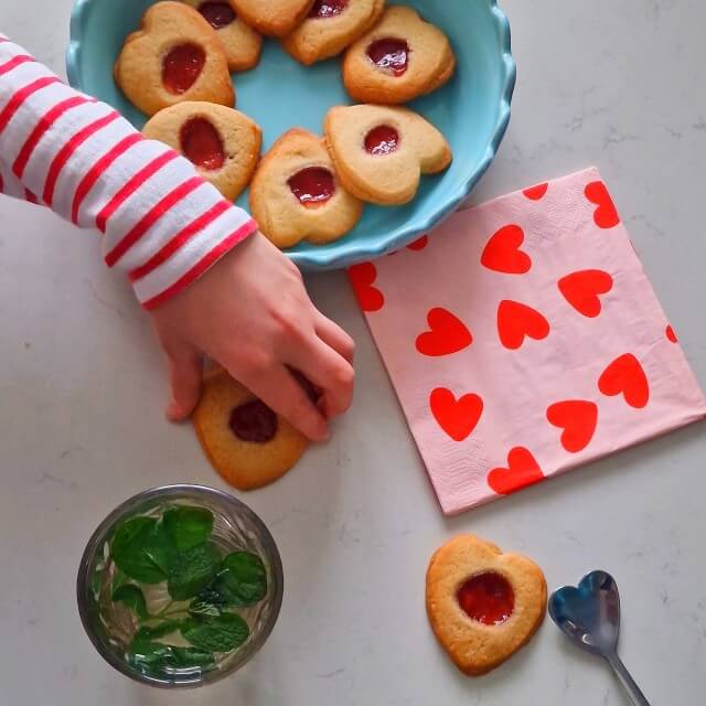 Hartjes koekjes bakken voor Valentijnsdag. De kinderen zijn altijd op zoek naar een smoes om koekjes te bakken en te versieren. Dit keer was de smoes Valentijnsdag, een perfecte reden voor het bakken van koekjes! Zoals deze hartjes koekjes met jam in het midden voor Valentijnsdag.